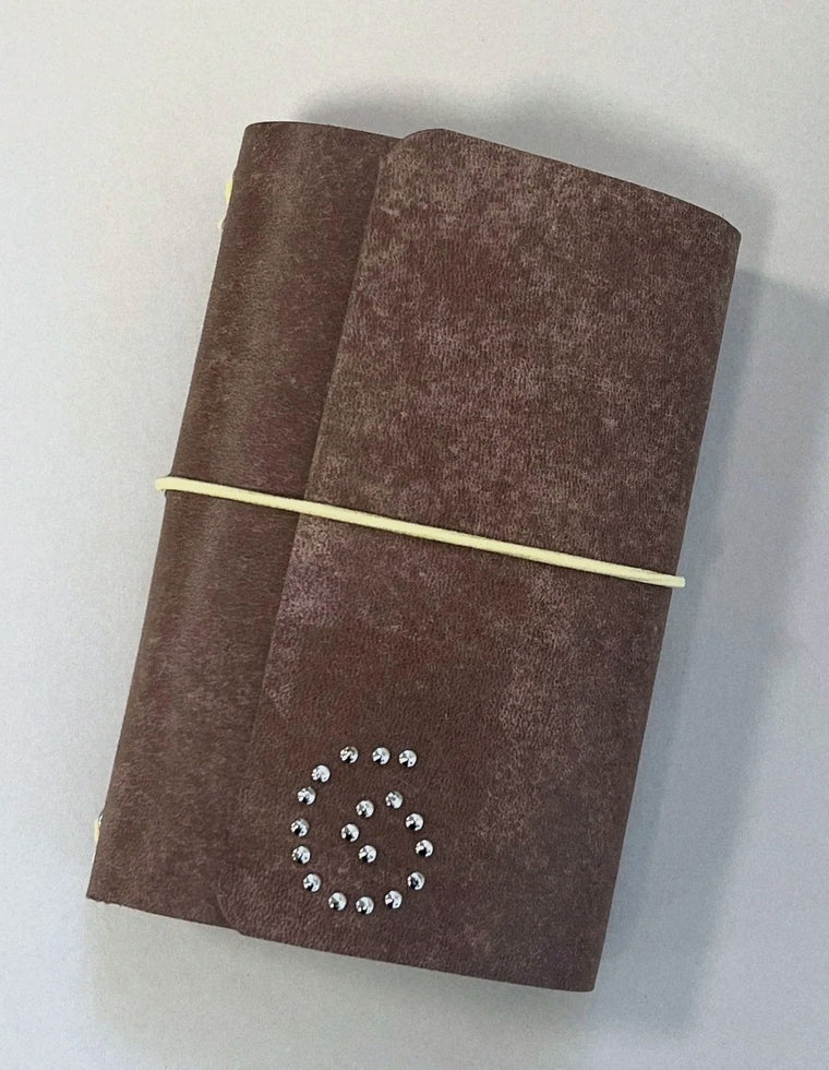 The Spiral Field Journal in brown patina leather with butter yellow elastic