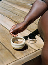 Hands mixing a face mask in a handmade ceramic bowl